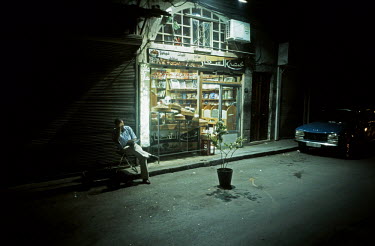 A man sits on a chair reading a book outside his late opening shop near the the Al-Hamidiyah Souq.