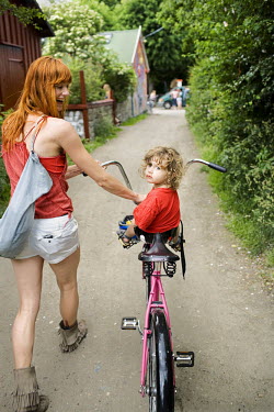 A woman and a child on a bicycle in the Christiania neighbourhood of Copenhagen.