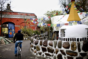A man rides a bicycle past a mock Buddhist stupa in the Christiania neighbourhood of Copenhagen.