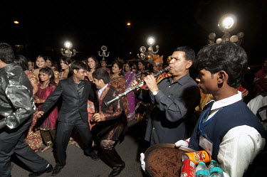 People play music and dance at a middle class wedding procession as they make their way to the bride's house.