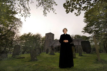 The Reverend Louise Spraggat poses in front of Saint Mary's Church of England Parish Church in Embsay, North Yorkshire.