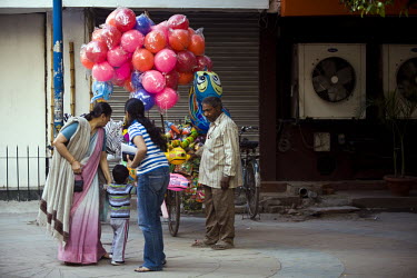 Ram Pal Gupta, a homeless balloon seller that lives beneath a bridge next to railway tracks in Okhla waits in a local market for a middle class family to buy his balloons.