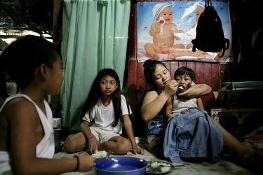 The Colandog family eats dinner at their home in the Santo Nino shanty town in Manila. People in this area live in small homemade huts, many made entirely from rubbish and leftover building materials...