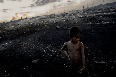 A homeless boy covered in dirt at the city's toxic rubbish dump. The dump provides food and shelter for many homeless people.