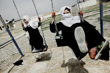 Two girls play on swings in the grounds of the Bazar-e Gharbi girls school.