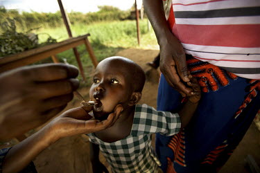 A young child is given a tablet during the Mother and Child Health Week held in April 2010. This includes a mass drug administration against intestinal worms and schistosomiasis. Around 14 million 16...
