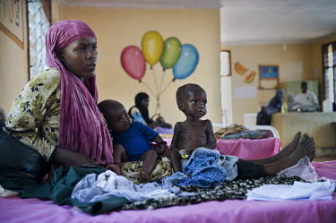 A woman sits with her children on a bed in the supplementary feeding ward at a hospital run by IRC (the International Rescue Committee) at Dadaab refugee camp. Since Al Shabaab, an Islamic militia wit...