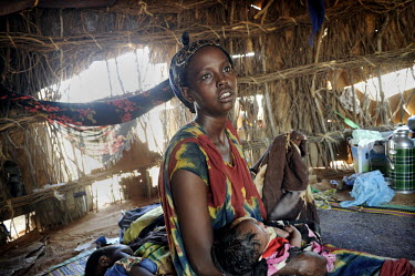 A woman holds her baby in their makeshift tent at Dadaab refugee camp. Since Al Shabaab, an Islamic militia with alleged links to Al Qaida, is controlling large parts of Somalia and imposing tough Sha...