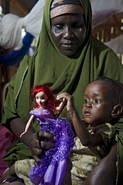 Saadia, suffering with malnourishment, plays with a doll as she is held by her mother in the stabilisation ward at a hospital at Dadaab refugee camp. Since Al Shabaab, an Islamic militia with alleged...