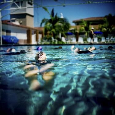 73 year old Margo Bouer swimming on her back in a pool during Aquadette practice at Laguna Woods, California. Margo suffers from severe MS, but says her nausea and shaking almost disappear when she is...