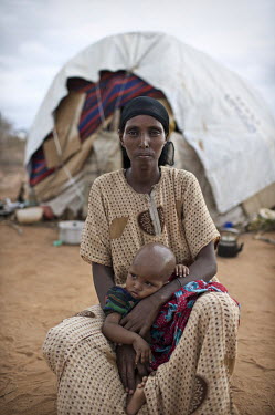 A portrait of 35 year old Habiba Ibrahim Iftin with one of her three children outside her hut at the Dadaab refugee camp. The youngest child is one year old; the others are four and six. When they cam...