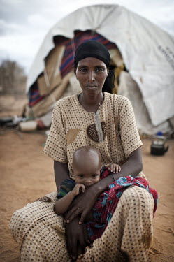 A portrait of 35 year old Habiba Ibrahim Iftin with one of her three children outside her hut at the Dadaab refugee camp. The youngest child is one year old; the others are four and six. When they cam...