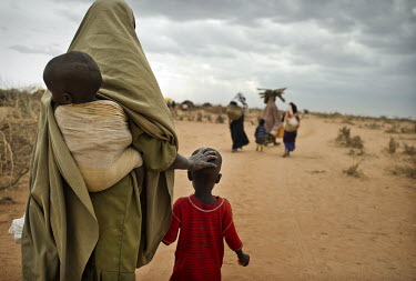 A woman and her children move to the IFO extension camp, a new part of the Dadaab refugee camp. Many of the recent arrivals at Dadaab are fleeing East Africa's worst drought for 60 years. The UN descr...