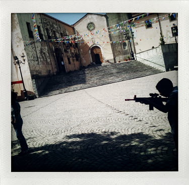 A boy plays with a toy gun outside of a church during the Festival of Madonna dei Martiri in Fonni, Sardinia.