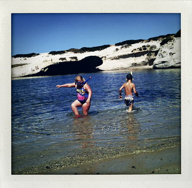 Children play on the shore by a beach at S'Archittu, Sardinia.