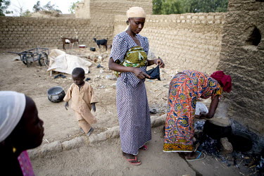 Sole, the first wife of Hamidou, cooks food in the front yard early in the morning. Ouma (14), his second wife, stands in the background. In Niger, three out of every four women are married before the...