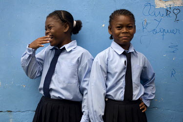 Twin sisters stand outside a school building after being late, on the island of Limones.