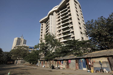 A modern high rise building with slum dwellers in front.