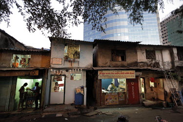 Shops and crumbling old slum buildings in front of a modern office building in the Arya Nagar area of Mumbai.