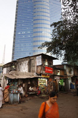 Shops and crumbling old slum buildings in front of a modern office building in the Arya Nagar area of Mumbai.