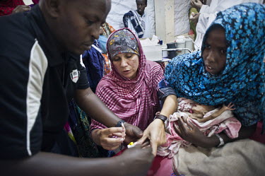 Karin Fisher (centre) from Medcins Sans Frontieres (MSF) works with medical staff to insert an intravenous line into the arm of a severely malnourished child in Galcayo hospital. Galcayo is a town in...