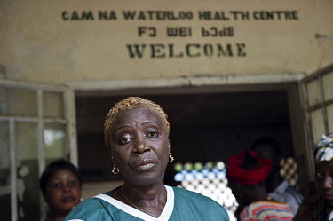 A nurse stands at the entrance of the health centre in the village of Waterloo. A year ago Sierra Leone launched a free healthcare plan for pregnant women, breast-feeding mothers and children under fi...