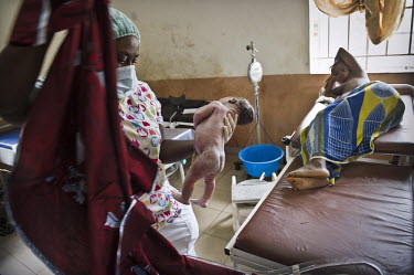 A midwife holds a newborn baby as the mother looks on at the regional hospital in Makeni. A year ago Sierra Leone launched a free healthcare plan for pregnant women, breast-feeding mothers and childre...