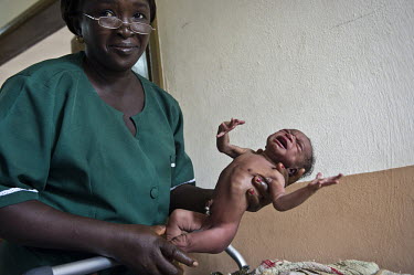 A nurse holds a newborn baby at the regional hospital in Makeni. A year ago Sierra Leone launched a free healthcare plan for pregnant women, breast-feeding mothers and children under five years old, b...