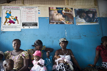 Women sit with their children as they wait for their children to have free treatment and vaccinations at the health centre in the village of Tumbu. A year ago Sierra Leone launched a free healthcare p...