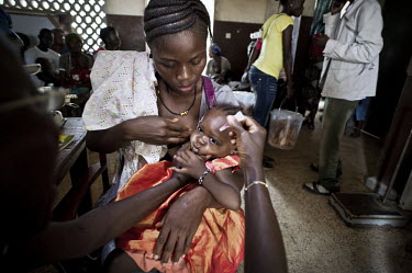 A child is held by her mother as she is vaccinated against polio at a health centre in the village of Waterloo. A year ago Sierra Leone launched a free healthcare plan for pregnant women, breast-feedi...