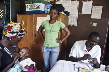 A child breastfeeds from its mother as a doctors assistant stands by at a health centre in the village of Waterloo. A year ago Sierra Leone launched a free healthcare plan for pregnant women, breast-f...