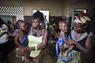 Mothers wait for their children to be weighed at a health centre in the village of Waterloo. A year ago Sierra Leone launched a free healthcare plan for pregnant women, breast-feeding mothers and chil...