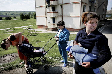 Viorica Belaia breast feeds her baby while standing outside an apartment with two friends. She works at the the Bucuria vineyard in South Moldova where she is paid about 15 GBP each month.