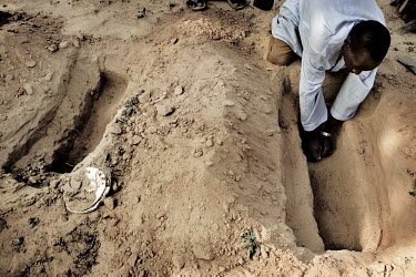 An Imam's aide digs graves for famine victims in the hot sand. The Imam and his aide buried more than 80 children in a period of about two months.