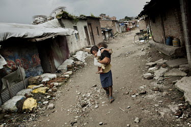 A small girl carrying a half naked young boy along a street in one of Kathmandu's slum neighbourhoods.