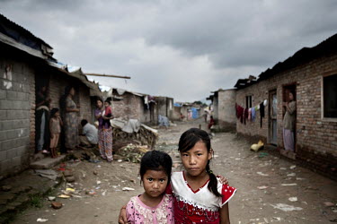 Two young girls stand arm-in-arm on a street in one of Kathmandu's slum neighbourhoods.