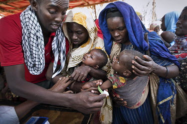 An aid worker takes a mid-upper arm circumference (MUAC) measurement from a child bought to a feeding centre by its mother. The centre is in a camp for internally displaced people (IDPs) near the vill...