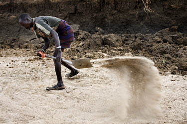 A man digs for a water source in a dried out river bed.