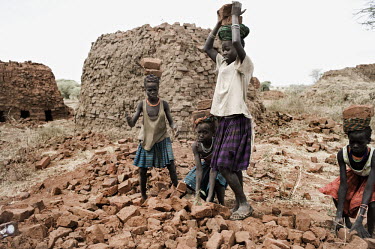 Young girls collect loads of bricks at the factory where they work.