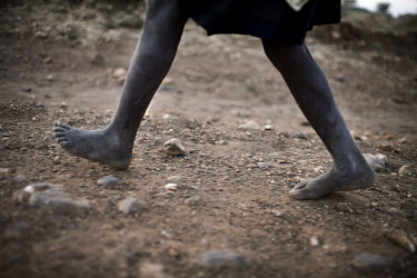 A young girl walks along a dusty path with a load of firewood.