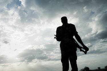 A soldier armed with a Kalashnikov PKS machine gun prepares to guard some livestock from raiders.