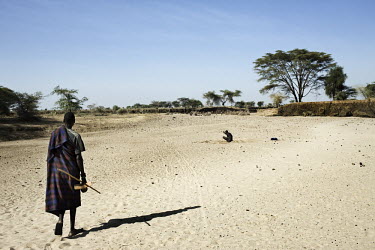 A man searches for a water source in a dry river bed.