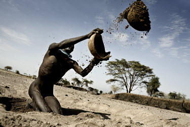 A man digs for water in a dry river bed.