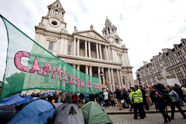 Police stand by tents and a large banner reading 'Capitalism is crisis' at the Occupy the London Stock Exchange protest outside St Paul's Cathedral in London. The rally is part of a worldwide protest...