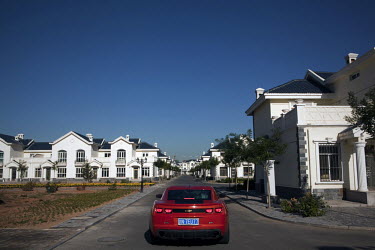 A sports car is driven through an exclusive villa complex in Ordos. The Kangbashi District of Ordos, a district planned, five years ago, for 1 million inhabitants, still lies almost dormant and has be...