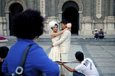 A newly wed couple have their wedding photographs taken in a central Beijing Square.
