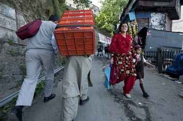 A porter carries crates of soft drinks, past a mother and schoolboy, up one of Shimla's steeply inclined streets. The city's steep, narrow streets and an abundance of staircases means most goods have...