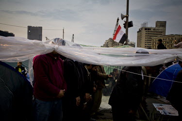 Men pray in beneath a tarpaulin cover erected in Tahrir Square. 25 January 2011 saw the beginning of a nationwide 18 day protest movement that eventually ended the 30-year rule of Hosni Mubarak and hi...