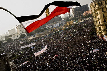 An Egyptian flag flies over hundreds of thousands of anti-government protesters filling Tahrir Square. 25 January 2011 saw the beginning of a nationwide 18 day protest movement that eventually ended t...