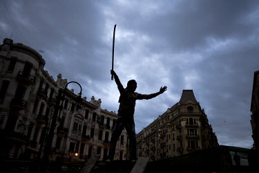 An anti-government protester holds a sword aloft as he stands on a road block at an entrance to Tahrir square. 25 January 2011 saw the beginning of a nationwide 18 day protest movement that eventually...